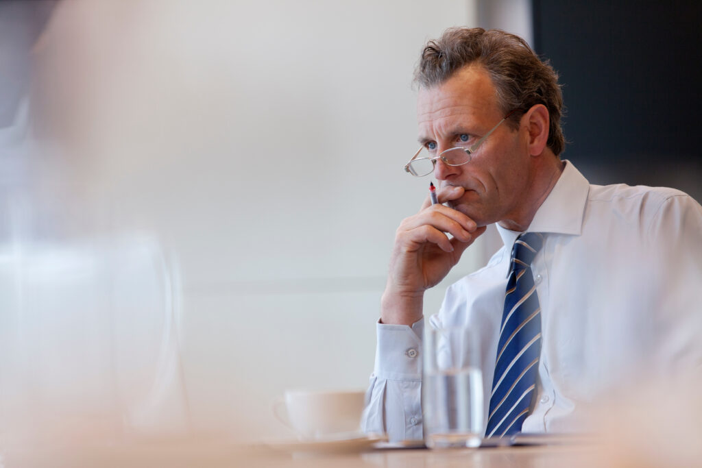 Serious corporate businessman listening in conference room meeti